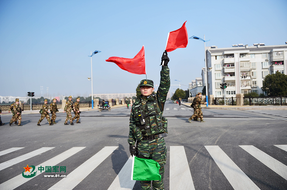 警戒分队一名战士用旗语警示过往车辆保障官兵行军安全.傅浩良 摄