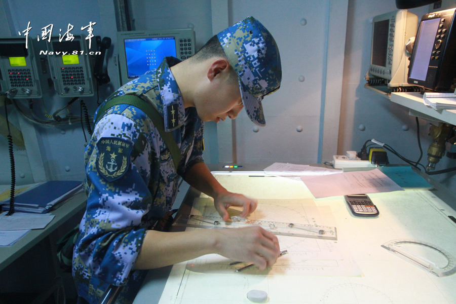长白山舰副航海长李晓龙正在海图上标绘